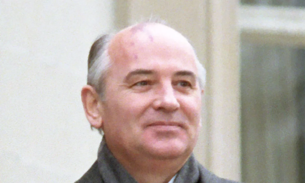 Colour portrait of Gorbachev, smiling, in a grey coat and scarf.
