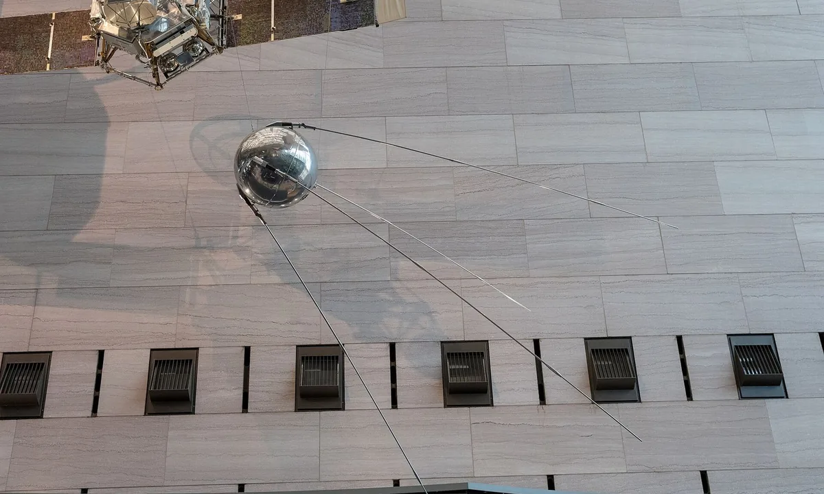 Photograph of a shiny metal sphere with four long thin antennas sweeping back from it.