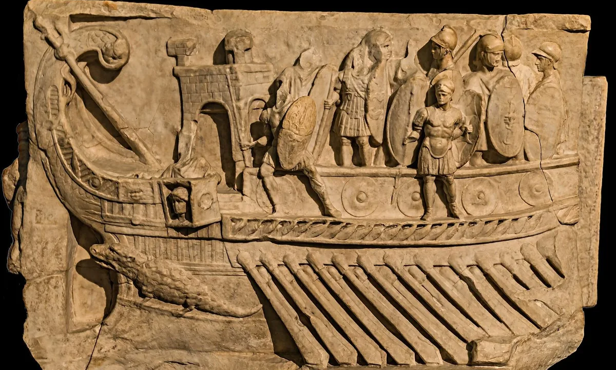 Marble relief of the front of a galley with a crowded deck of soldiers holding shields, and a crocodile carved on the prow.