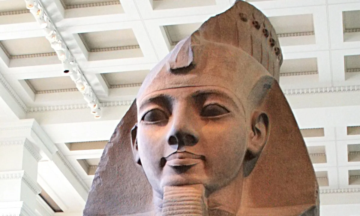 Huge two-tone granite head and shoulders of a calm young king wearing a striped headcloth with a cobra on the brow.
