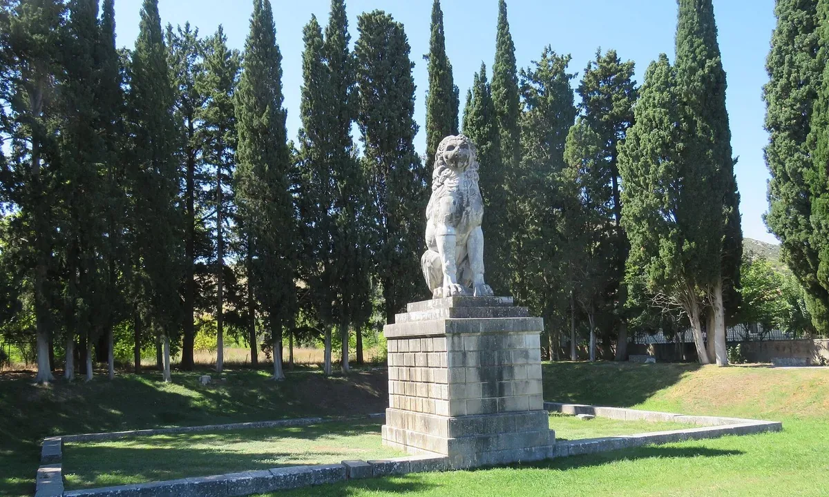 A large marble lion seated on a tall stone pedestal in a grassy enclosure ringed by cypress trees.