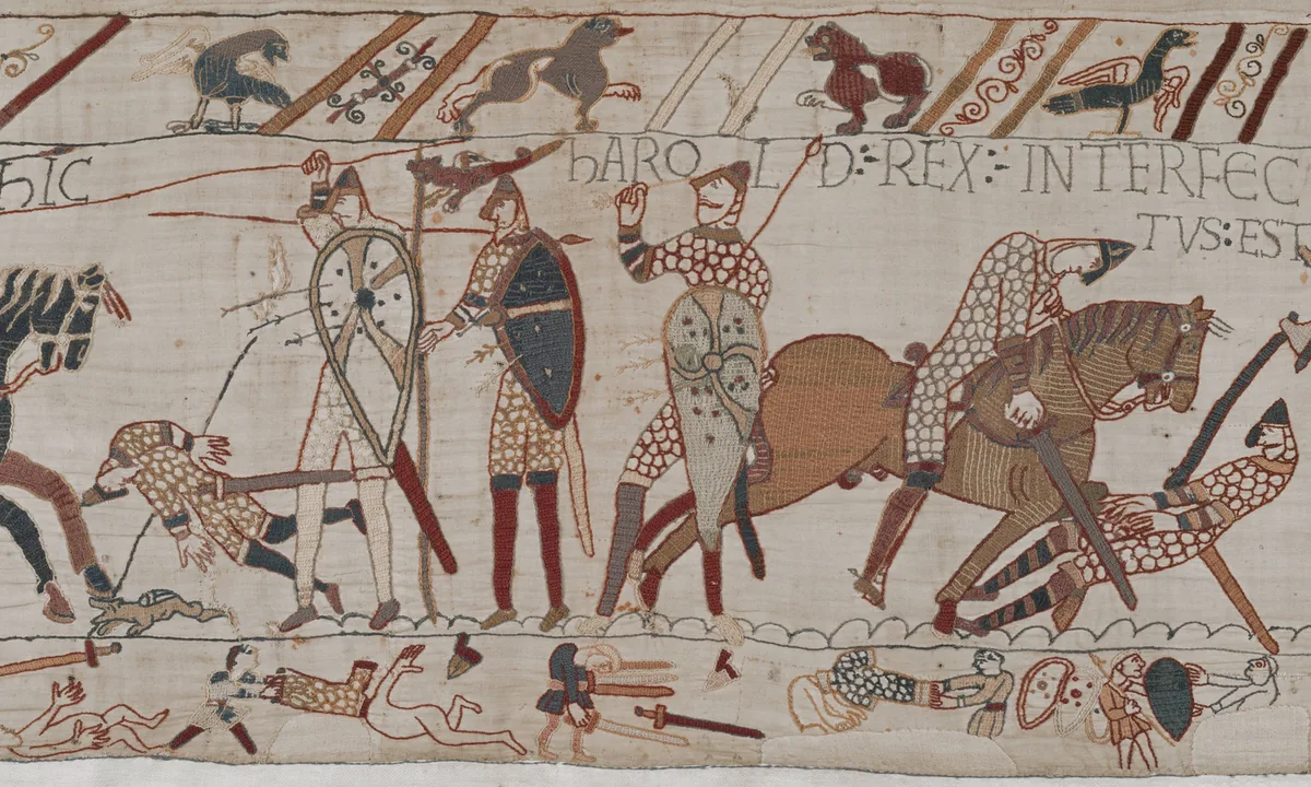 Embroidered frieze of mounted knights with lances and fallen soldiers, one figure gripping an arrow near his face, beneath a line of Latin lettering.