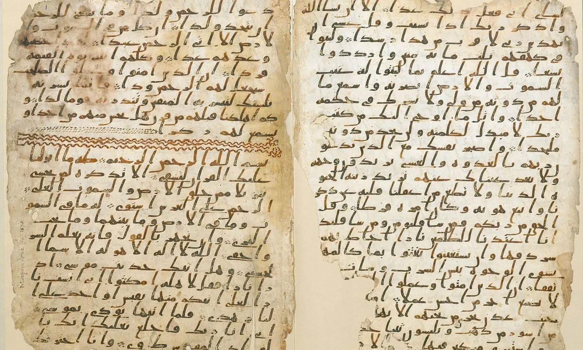 Two facing parchment leaves covered in dense lines of early angular Arabic script in dark ink, with a band of orange decoration between suras on the left leaf.