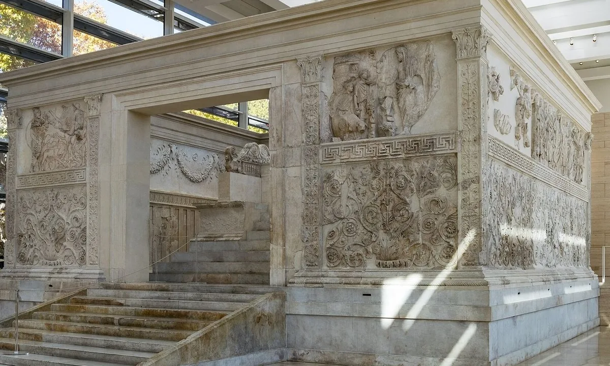 White marble altar enclosure with carved relief panels of processing figures and plant scrolls.