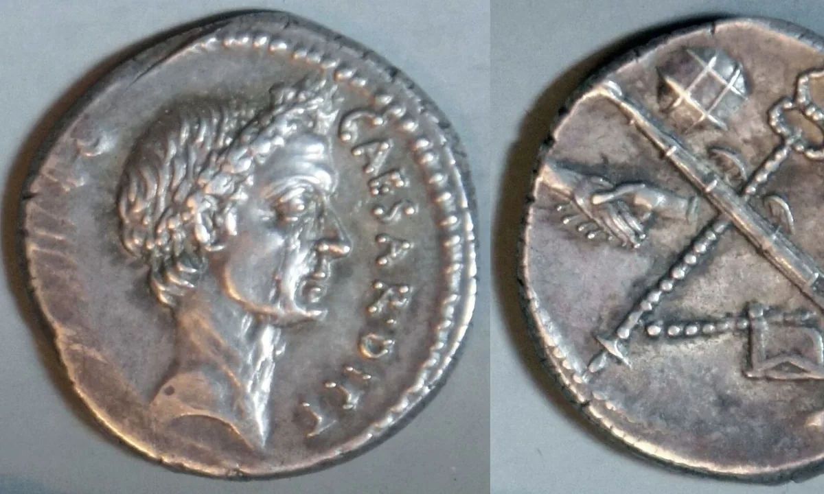 Silver Roman coin with the profile of a man wearing a wreath and Latin lettering around the edge.