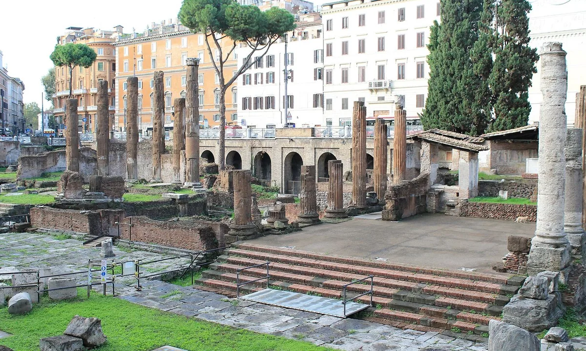 Sunken excavated area in a modern city square with columns and temple foundations.