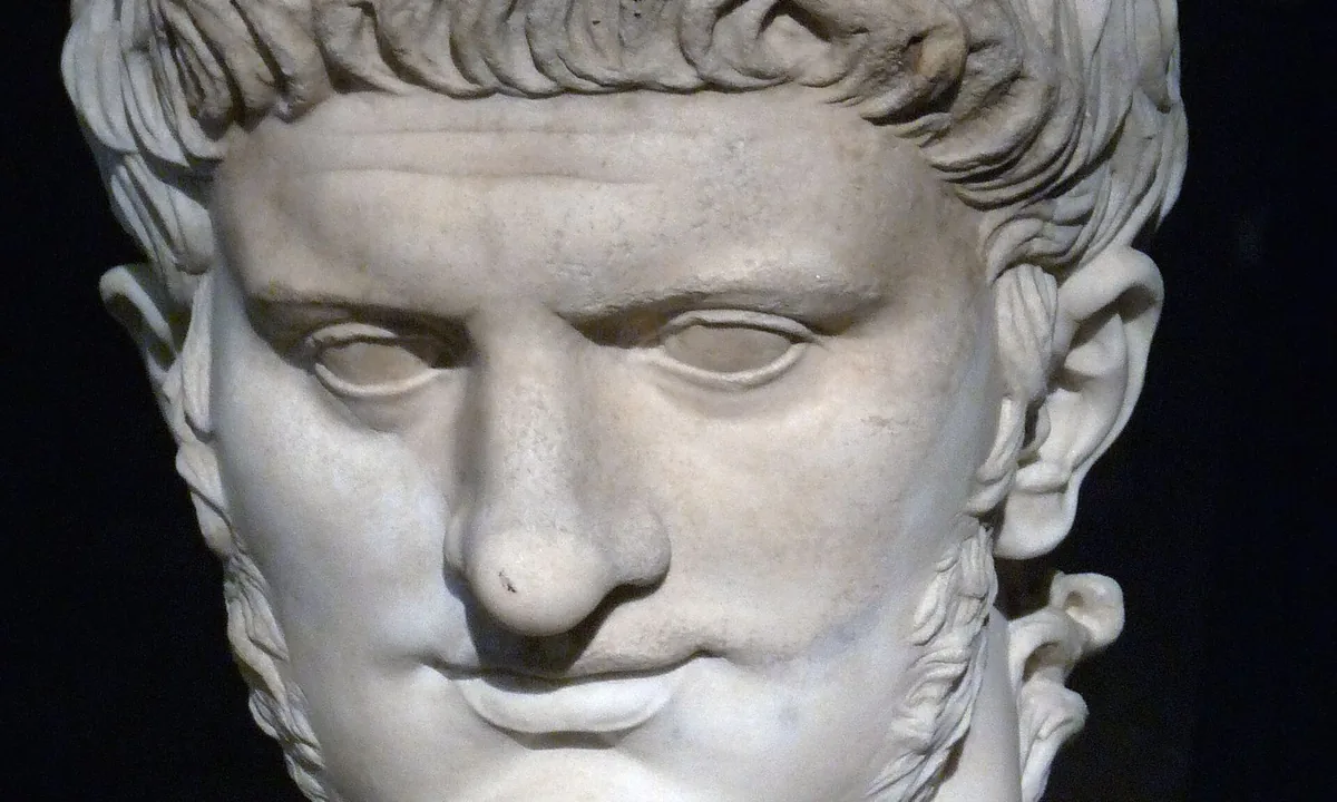 Marble head of a man with a fleshy face, heavy jaw, short side-whiskers and carefully curled hair combed forward over the forehead.