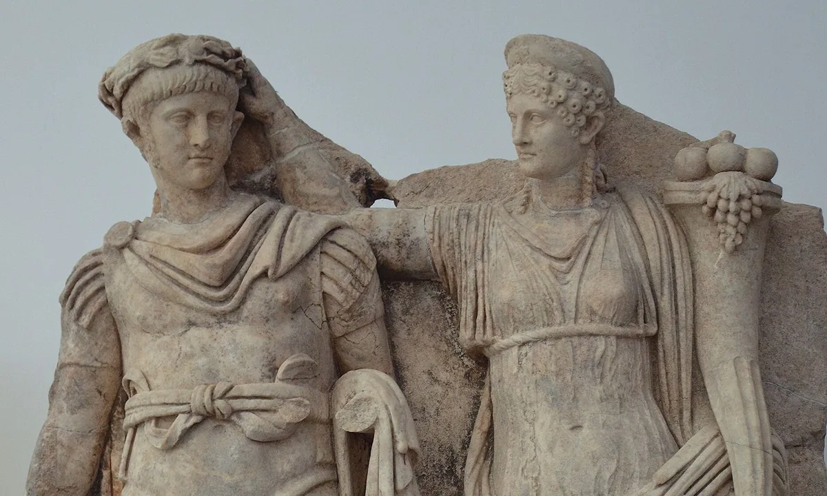 Marble relief of a young man in Roman armour and cloak beside a woman in a long robe holding a horn of fruit, who reaches over to place a wreath on his head.